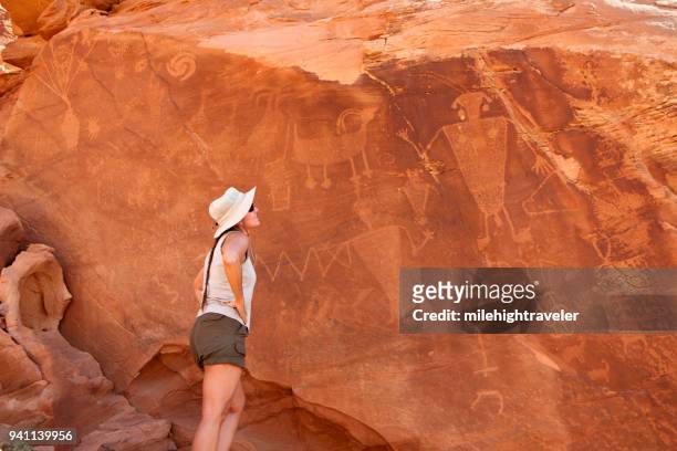 woman inspects native american fremont indian dinosaur national monument petroglyphs utah - dinosaur national monument stock pictures, royalty-free photos & images