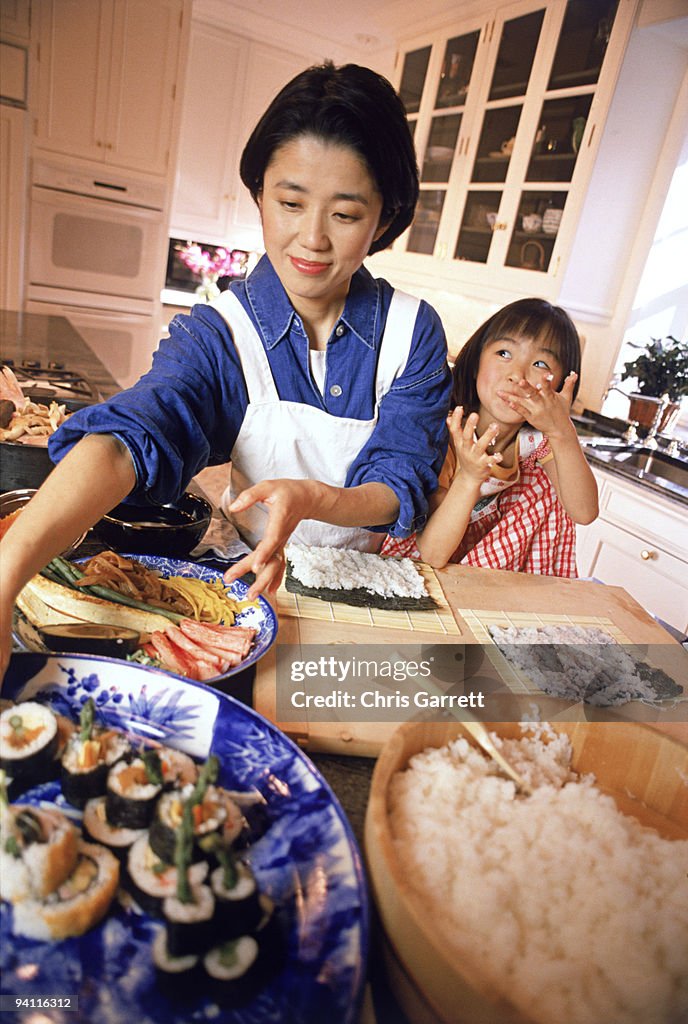 Mother and daughter in kitchen making sushi together