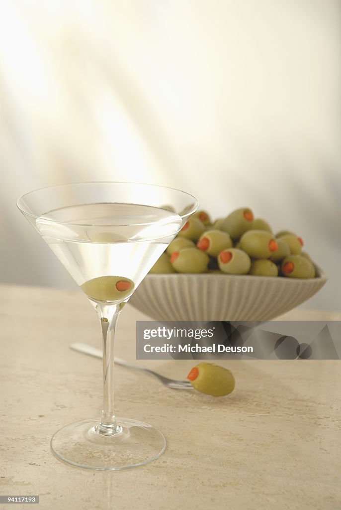 Martini with bowl of green olives