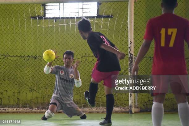 This picture taken on February 3, 2018 shows goalkeeper Eman Sulaeman attempting a save during a futsal match in Indramayu, West Java. - When Eman...