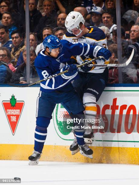 Connor Carrick of the Toronto Maple Leafs checks Casey Mittelstadt of the Buffalo Sabres during the second period at the Air Canada Centre on April...