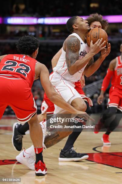 Bradley Beal of the Washington Wizards takes the ball off of his chin as he drives between Cameron Payne and Robin Lopez of the Chicago Bulls at the...