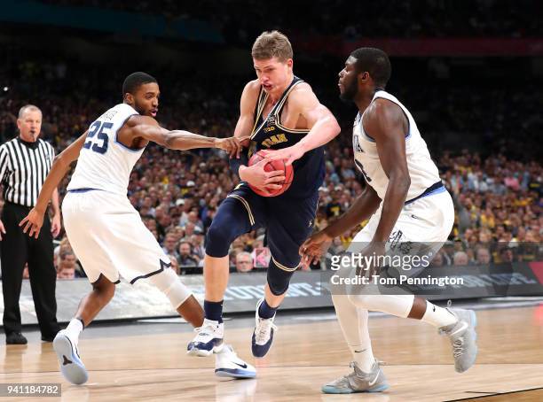 Moritz Wagner of the Michigan Wolverines drives with the ball against Mikal Bridges and Eric Paschall of the Villanova Wildcats in the first half...