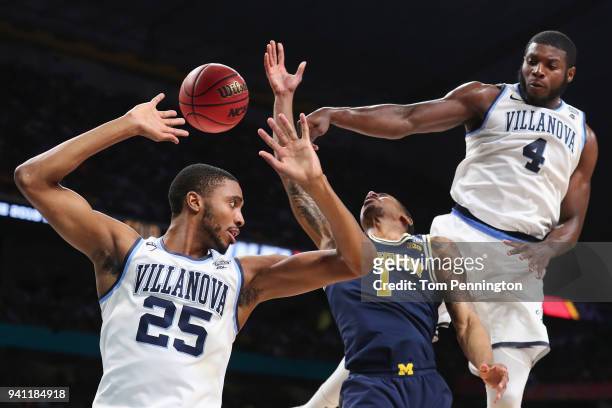 Mikal Bridges and Eric Paschall of the Villanova Wildcats defend Charles Matthews of the Michigan Wolverines in the first half during the 2018 NCAA...