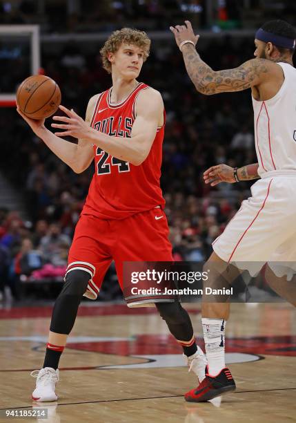 Lauri Markkanen of the Chicago Bulls looks to pass against Mike Scott of the Washington Wizards at the United Center on April 1, 2018 in Chicago,...