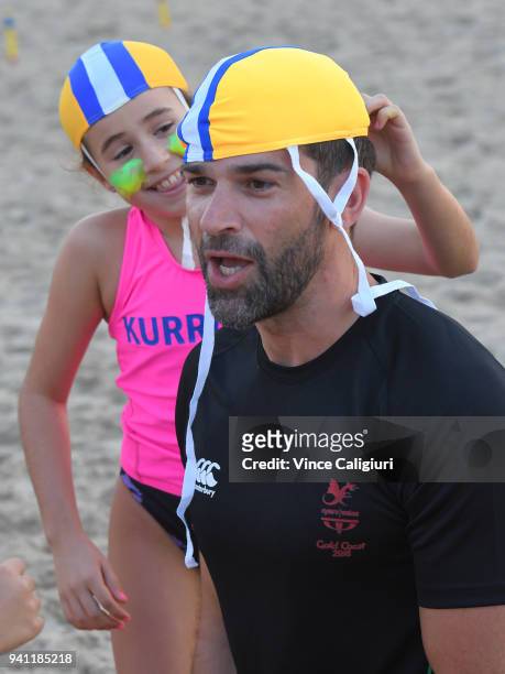 Welsh Television presenter, Gethin Jones is helped putting on his cap by Kurrawa Surf Life Saving nippers ahead of the 2018 Gold Coast Commonwealth...