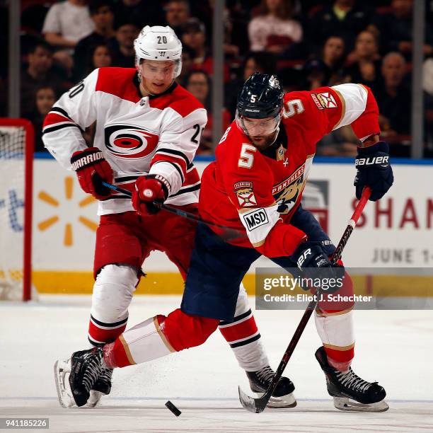 Aaron Ekblad of the Florida Panthers skates for possession against Sebastian Aho of the Carolina Hurricanes at the BB&T Center on April 2, 2018 in...