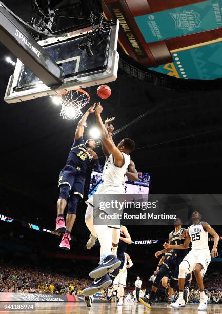 Muhammad-Ali Abdur-Rahkman of the Michigan Wolverines drives to the basket against Phil Booth of the Villanova Wildcats in the first half during the...