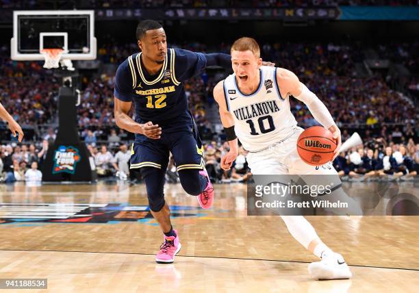 Donte DiVincenzo of the Villanova Wildcats drives to the basket against Muhammad-Ali Abdur-Rahkman of the Michigan Wolverines during the first half...