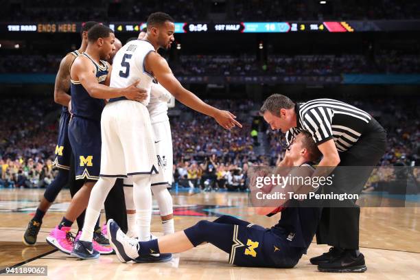 Phil Booth of the Villanova Wildcats and Moritz Wagner of the Michigan Wolverines exchange words after competing for a loose ball in the first half...