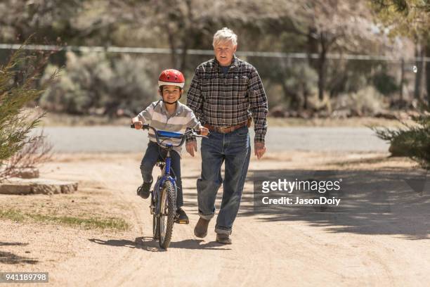 grandfather teaching grandson bicycle riding - jasondoiy imagens e fotografias de stock