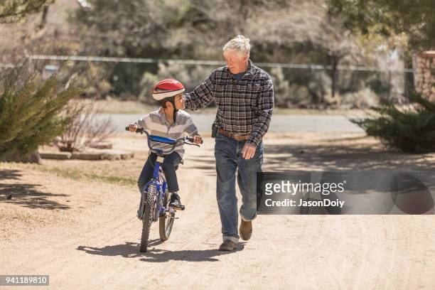 nieto de abuelo enseñanza bicicleta - jasondoiy fotografías e imágenes de stock
