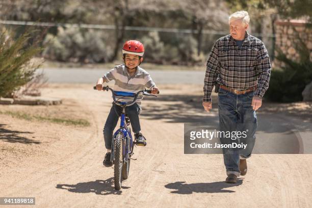 grandfather teaching grandson bicycle riding - jasondoiy stock pictures, royalty-free photos & images