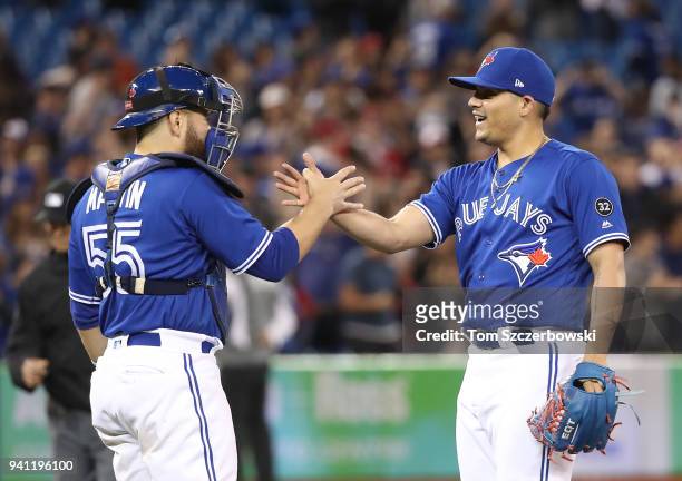 Catcher Russell Martin of the Toronto Blue Jays celebrates a win over the Chicago White Sox with Roberto Osuna at Rogers Centre on April 2, 2018 in...