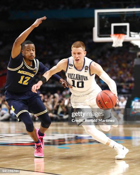 Donte DiVincenzo of the Villanova Wildcats is defended by Muhammad-Ali Abdur-Rahkman of the Michigan Wolverines in the first half during the 2018...