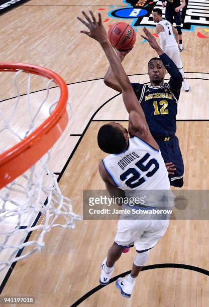 Muhammad-Ali Abdur-Rahkman of the Michigan Wolverines shoots the ball over Mikal Bridges of the Villanova Wildcats during the first half of the 2018...