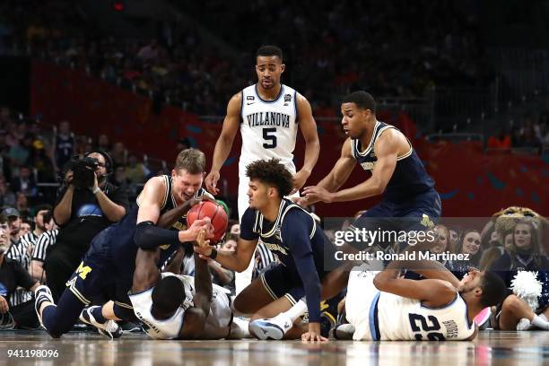 Eric Paschall and Mikal Bridges of the Villanova Wildcats compete for a loose ball with Isaiah Livers of the Michigan Wolverines in the first half...