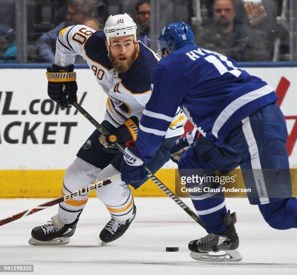 Ryan O'Reilly of the Buffalo Sabres skates with the puck against Zach Hyman of the Toronto Maple Leafs during an NHL game at the Air Canada Centre on...