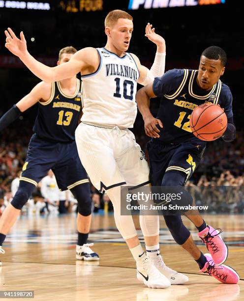 Muhammad-Ali Abdur-Rahkman of the Michigan Wolverines drives the ball around Donte DiVincenzo of the Villanova Wildcats during the first half in the...