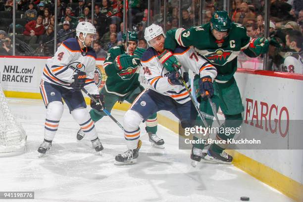 Ethan Bear and Kris Russell of the Edmonton Oilers battle for the puck with Zach Parise and Mikko Koivu of the Minnesota Wild during the game at the...