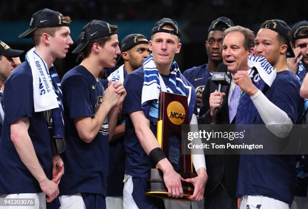 Donte DiVincenzo of the Villanova Wildcats holds the trophy while celebrating with teammates after defeating the Michigan Wolverines during the 2018...