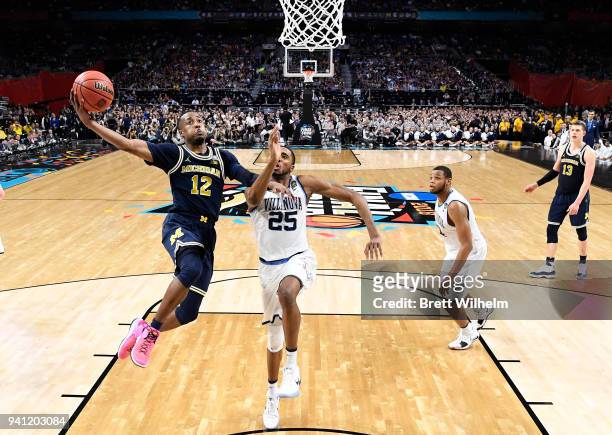 Muhammad-Ali Abdur-Rahkman of the Michigan Wolverines drives to the basket against Mikal Bridges of the Villanova Wildcats during the second half of...