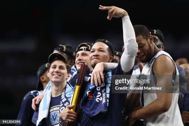 Collin Gillespie and Jalen Brunson of the Villanova Wildcats watch "One Shining Moment" while celebrating after defeating the Michigan Wolverines...