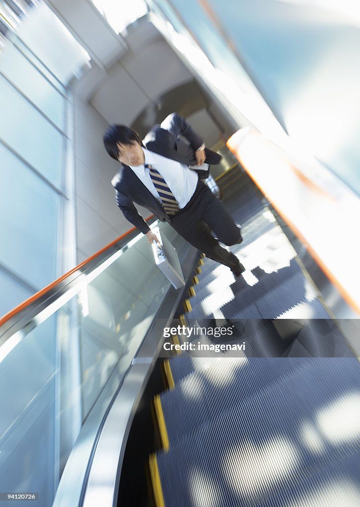 Businessman running up escalator