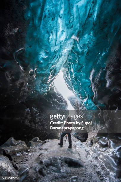 traveler standing at ice cave in vatnajokull water glacier that is the largest and most voluminous ice cap in iceland - iceland cave stock pictures, royalty-free photos & images