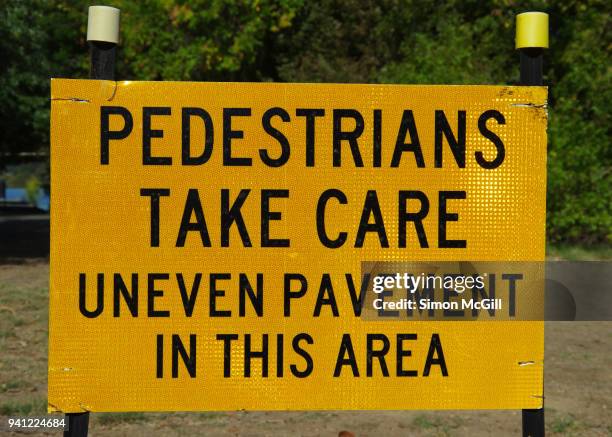 'pedestrians take care: uneven pavement in this area' sign - trip hazard stock pictures, royalty-free photos & images