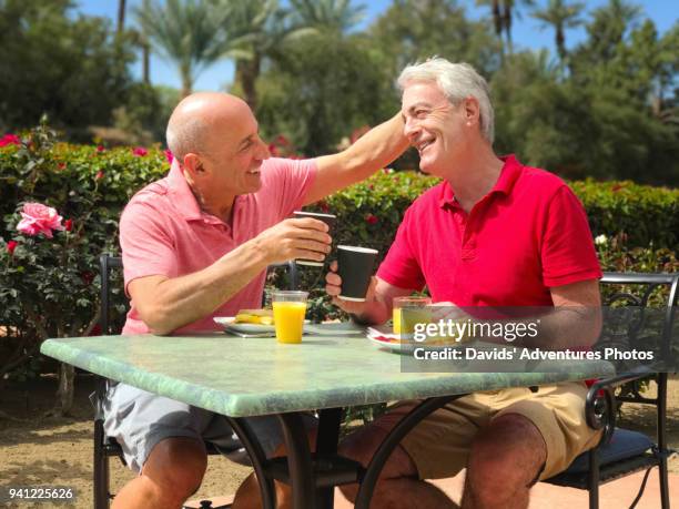 older gay couple on vacation having breakfast at a small outdoor table on sunny morning - pension stock-fotos und bilder