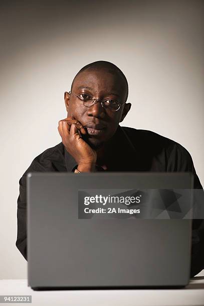 young professional looking into camera over a laptop, johannesburg, gauteng province, south africa - gauteng province stockfoto's en -beelden