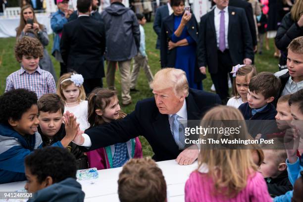 President Donald J. Trump greets children as he sits at a table to sign messages in support of U.S. Troops during the 2018 White House Easter Egg...
