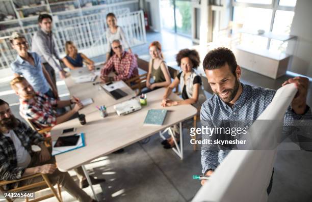 above view of happy entrepreneur explaining the business plan to his team on a presentation in the office. - brainstorming stock pictures, royalty-free photos & images