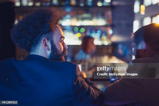 three businessman having fun after work, sitting on the bar counter - man business hipster dark smile stock pictures, royalty-free photos & images