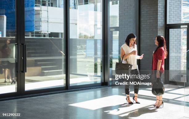 two adult women talk in the building - finance talk stockfoto's en -beelden