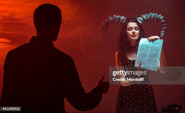 young man enters into contract with female devil - devil woman stock pictures, royalty-free photos & images