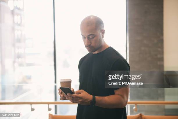 a young maori and caucasian mixed man is using his cellphone - photohui17 stock-fotos und bilder