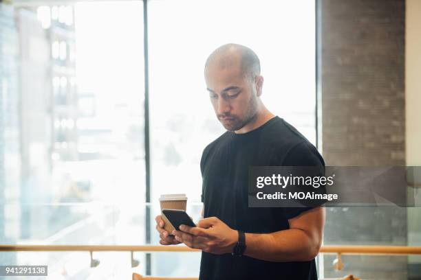 a young maori and caucasian mixed man is using his cellphone - photohui17 stock-fotos und bilder