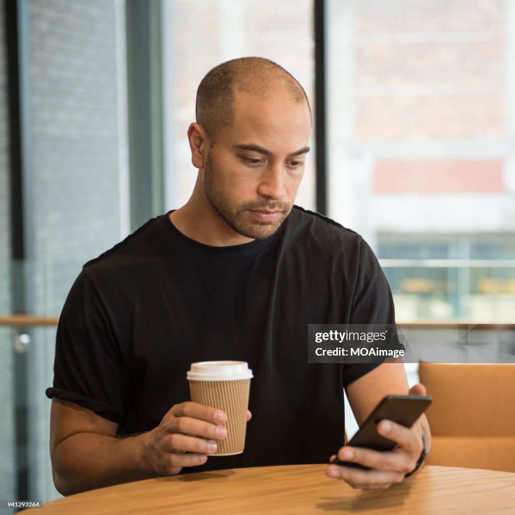 A young Maori and Caucasian mixed man is using his cellphone