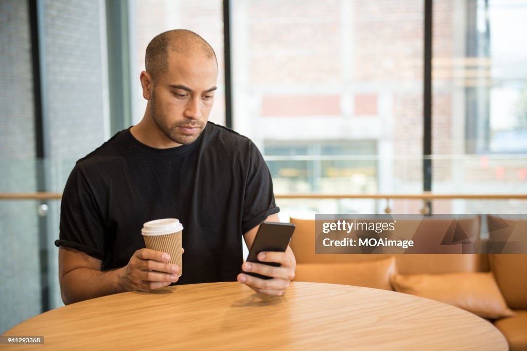 A young Maori and Caucasian mixed man is using his cellphone