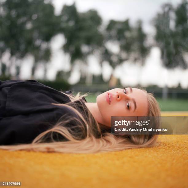portrait of beautiful young woman lying on tennis court - andriy onufriyenko stockfoto's en -beelden