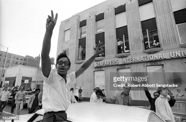 Protestors wave their fingers in peace symbols as they walk past the Seafarers International Union building during the Grant Park demonstrations held...