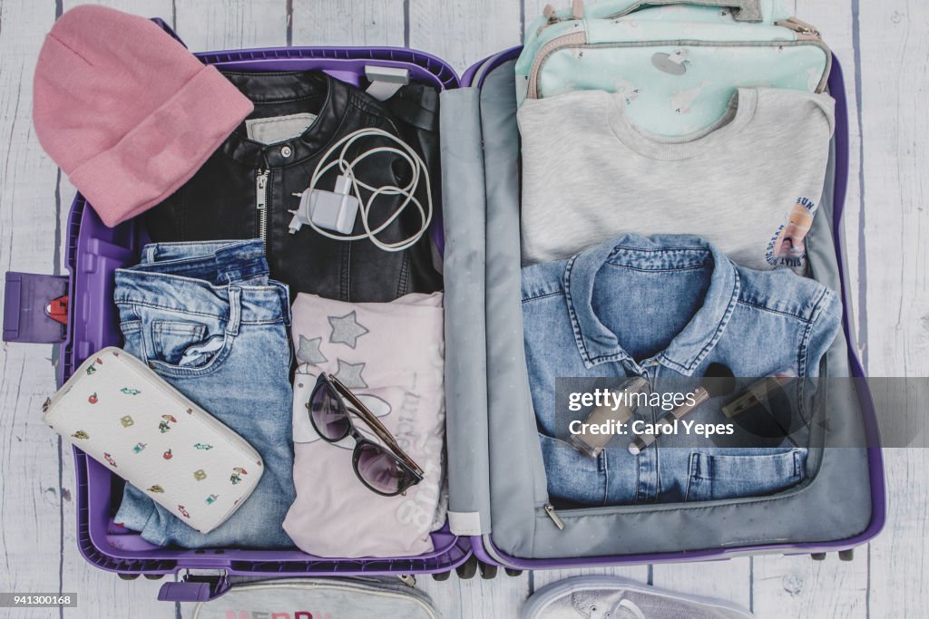 Open suitcase with casual female clothes