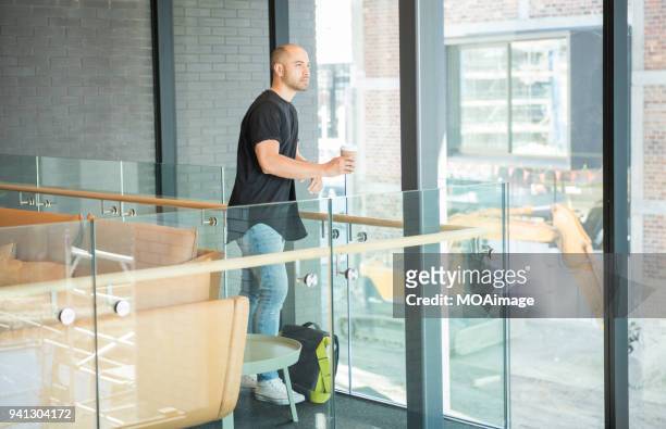 a young maori and caucasian mixed man is standing by the window - photohui17 stock-fotos und bilder