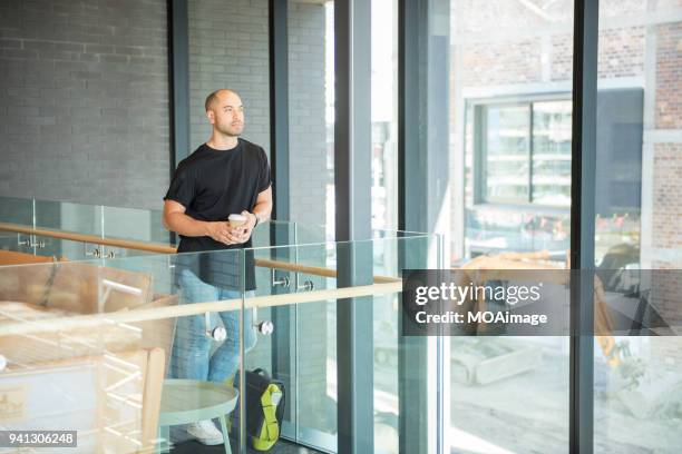 a young maori and caucasian mixed man is standing by the window - photohui17 stock-fotos und bilder