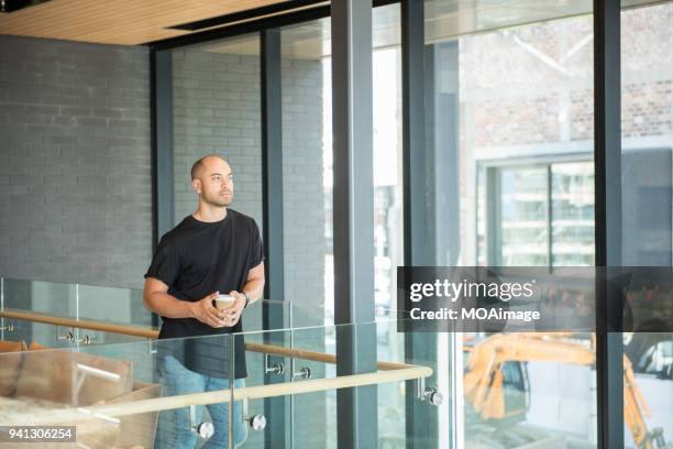 a young maori and caucasian mixed man is standing by the window - photohui17 stock-fotos und bilder