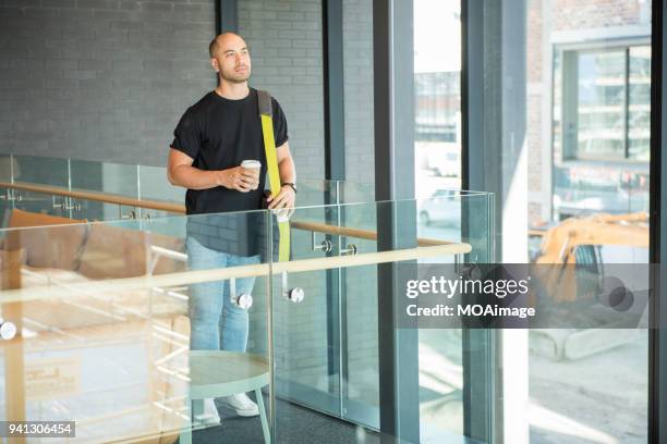 a young maori and caucasian mixed man is standing by the window - photohui17 stock-fotos und bilder