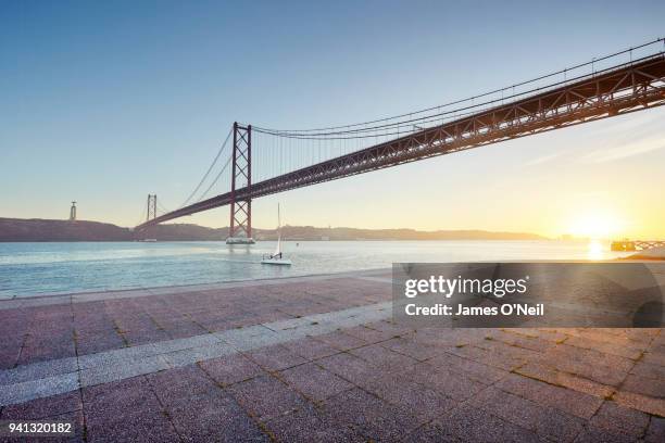 ponte 25 de abril at sunset with foreground paving, lisbon, portugal - puente 25 de abril fotografías e imágenes de stock