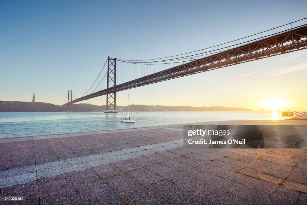 Ponte 25 de Abril at sunset with foreground paving, Lisbon, Portugal
